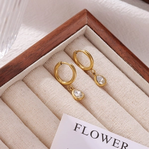 Golden hoop earrings with pear-cut zircon pendants displayed in a jewelry box
