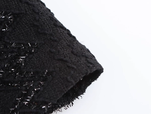 Close-up of black knit fabric with elegant texture and subtle sparkling fringe details