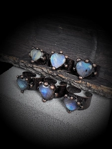 Artistic macro shot of vintage bronze heart moonstone rings on natural dark wood and stone