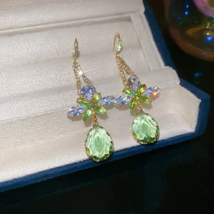 Close-up of light green teardrop zircon earrings displayed in a luxury blue jewelry box