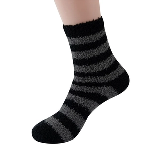 Men's striped coral fleece slipper socks in black and grey on a model leg