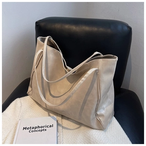 Macro detail of beige soft PU leather tote bag on a black chair with a cozy white blanket