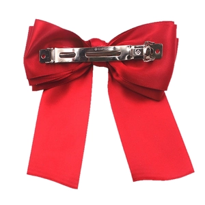 Classic red satin bow hair clip with silver metal spring clip on a white background