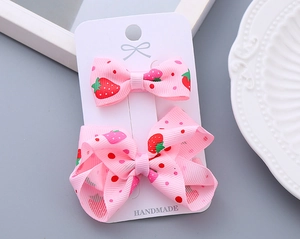 Detail of two pink strawberry print bow hair clips on handmade display card