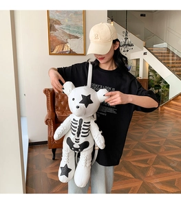 Detail of white bear-shaped backpack with skeleton print and black star accents