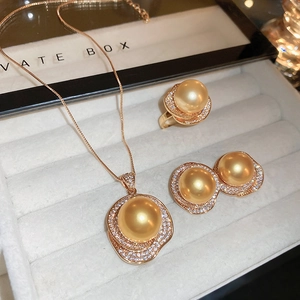 Gros plan sur parure bijoux perles dorées avec collier, bague et boucles d'oreilles