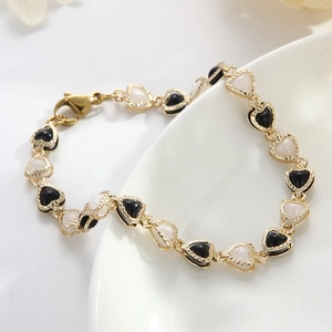 Minimalist gold heart link bracelet with black and white inserts on white ceramic