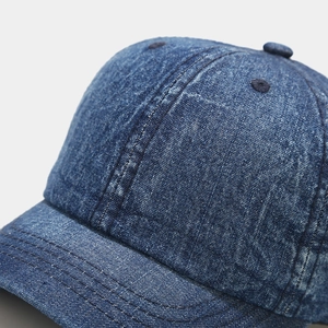 Detailed close-up of dark blue washed denim baseball cap with premium triple-stitched brim