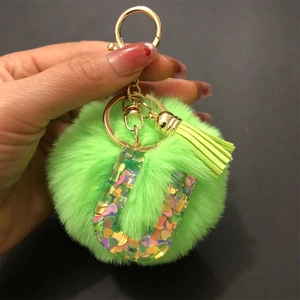 Detail of green fur pompom keychain with heart sequin resin letter U and gold clip