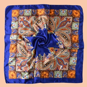 Detail of royal blue paisley silk scarf with intricate floral patterns and glossy texture