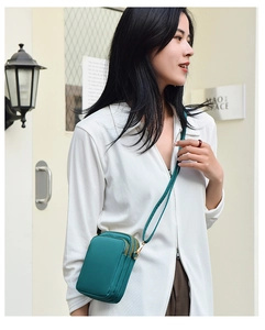 Green vertical crossbody phone bag with multiple zipper compartments shown on model