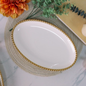 Detailed top view of white ceramic plate with gold beaded trim on woven placemat