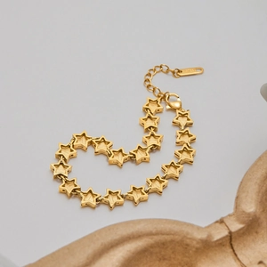 Close-up of golden stainless steel star-shaped link bracelet with matte and polished finish