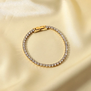Macro view of 14K gold plated tennis bracelet with sparkling cubic zirconia on satin