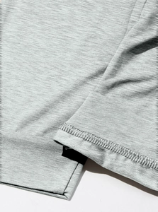 Dettaglio macro del tessuto a maglia grigio chiaro con texture melange e doppia cucitura