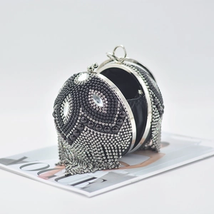 Detail of spherical evening clutch featuring silver rhinestones and long metal tassels