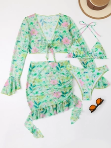 Flat lay of green floral four-piece bikini set with mesh cover-up and beach accessories