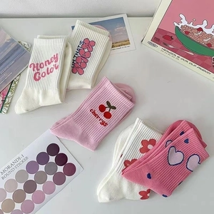 Vista piatta di calzini in cotone rosa e bianco con motivi a ciliegia e a cuore