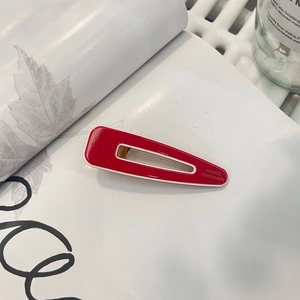 Detail of red handmade duckbill hair clip with France engraving on aesthetic book background