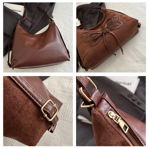 Detail of brown tote bag with suede texture, butterfly embroidery, and gold hardware