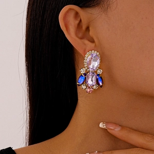Close-up of vintage gold earrings with oval purple gemstones on a female model