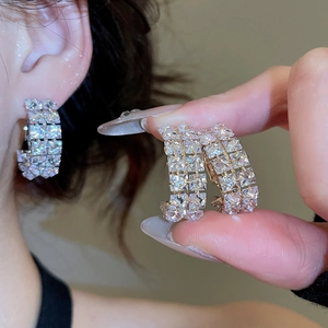 Close-up of C-shaped hoop earrings with double-row cubic zirconia on earlobe