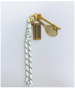Detailed shot of vintage bronze abacus and tennis racket pendants on braided rope keychain