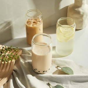 Three clear can-shaped glass cups filled with bubble tea, iced coffee, and lemonade drinks