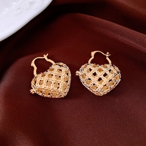 Macro shot of gold-finished heart hoop earrings featuring intricate mesh hollow design