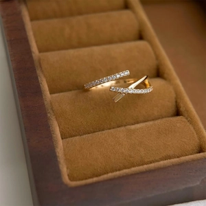 Detail shot of a golden crisscross ring with zircons in a luxury velvet jewelry box