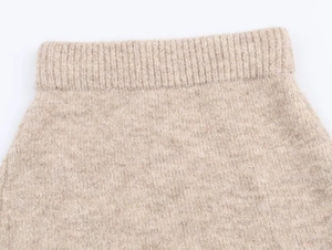 Dettaglio ravvicinato della trama a coste e del filato misto beige di questo capo in maglia