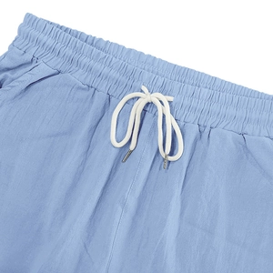 Détail du pantalon bleu clair avec taille élastique et cordon blanc à embouts métal