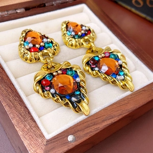 Macro detail of vintage triangle earrings with colorful gems in a velvet jewelry box