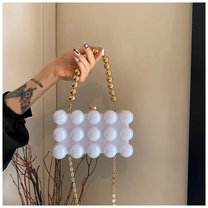 Detailed shot of white bubble-textured acrylic evening bag with gold orb handle