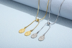 Detail of adjustable gold and silver snake chains with oval goddess embossed pendants