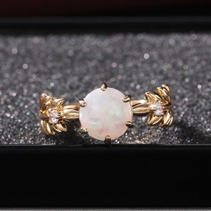 Macro di anello dorato stile natura con opale rotondo e dettagli di foglie in rilievo