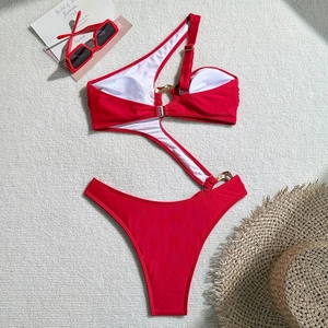 Detail of red one-shoulder monokini featuring waist cutouts and gold metal ring hardware