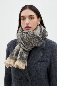 Detail of grey and beige leopard print scarf with soft fringe texture on a grey wool coat