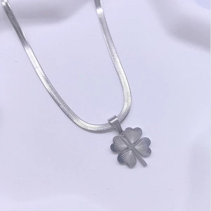 Silver four-leaf clover pendant necklace with flat snake chain on white fabric background