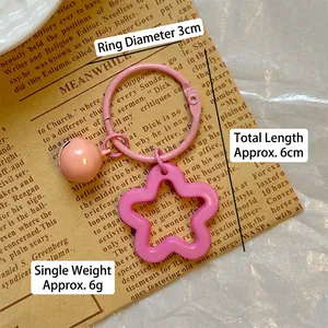 Pink floral acrylic keychain with matching bell and metal ring on vintage paper