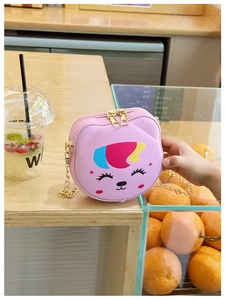 Detailed view of pink cat crossbody bag with golden chain in a bright cafe setting