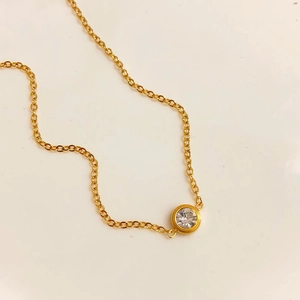 Detailed top view of a minimalist gold necklace with a single round clear zircon pendant