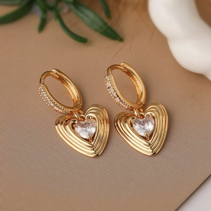 Boucles d'oreilles cœur dorées avec cristaux de zircon en gros plan à 45 degrés