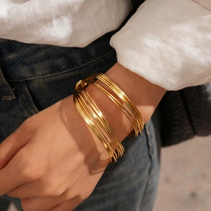 Close-up of golden multi-layer geometric twisted open bangle on a model wrist