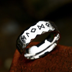 Primer plano de anillo vikingo de acero con grabados rúnicos sobre piedra texturizada