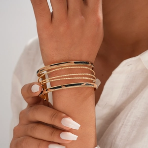 Bracciali sovrapposti in metallo dorato con motivo leopardato al polso di una modella