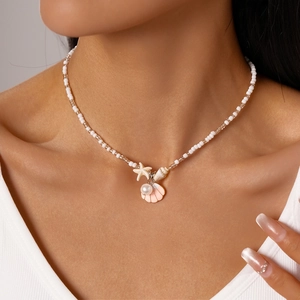 Detail of beach style beaded necklace with pearl, starfish, seashell and pink shell charm