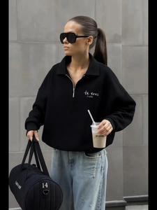 Detail of black half-zip sweatshirt featuring letter print and stylish polo collar style