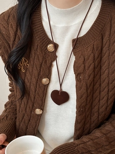 Close-up of a heart-shaped flocked resin pendant necklace worn on a brown knit sweater