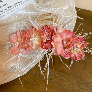 Détail d'une pince à cheveux avec fleurs en dentelle rose, papillon cristal et plumes
